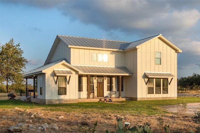 back of house featuring board and batten siding, a standing seam roof, covered porch, and metal roof