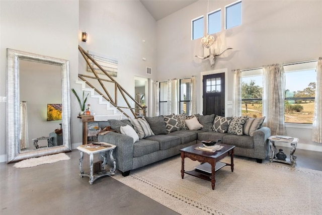 living room with stairs, finished concrete floors, a towering ceiling, baseboards, and visible vents