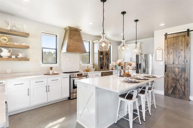 kitchen with premium range hood, concrete flooring, stainless steel appliances, and a barn door