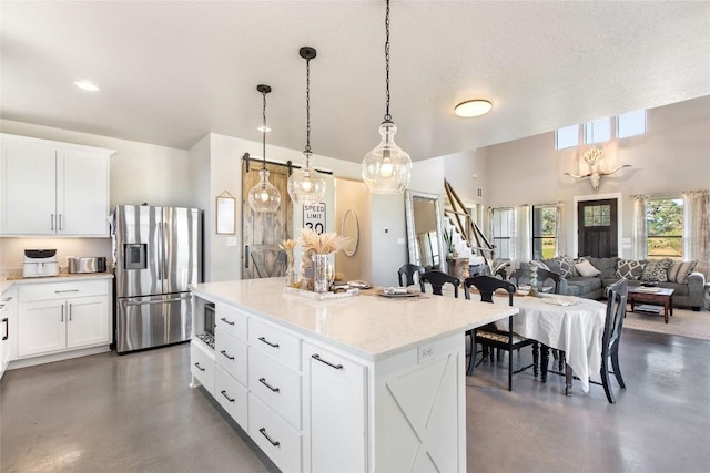 kitchen featuring concrete floors, a kitchen island, stainless steel refrigerator with ice dispenser, and white cabinetry