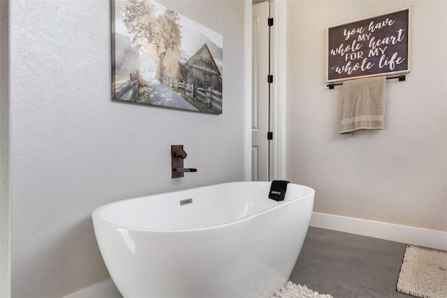 bathroom with baseboards and a freestanding tub