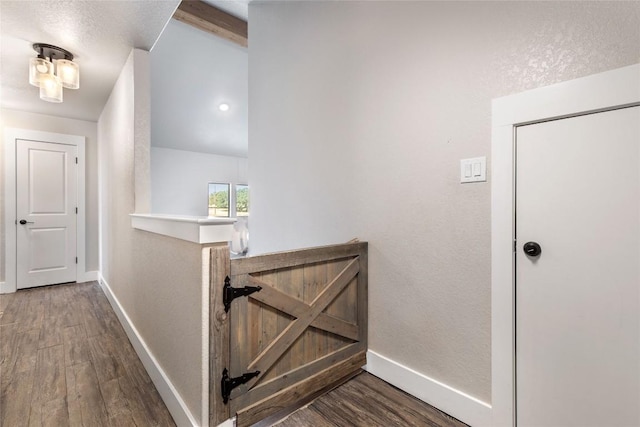 hall featuring wood finished floors, baseboards, and an upstairs landing