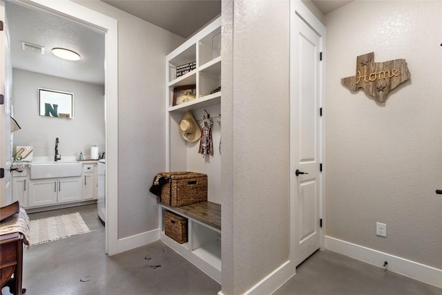 mudroom featuring concrete flooring, visible vents, baseboards, and a sink