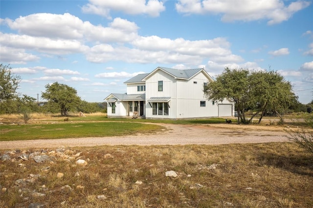 modern farmhouse featuring a standing seam roof, a front yard, driveway, and metal roof