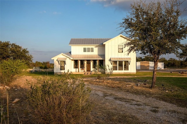 modern inspired farmhouse with a playground, board and batten siding, a standing seam roof, covered porch, and metal roof