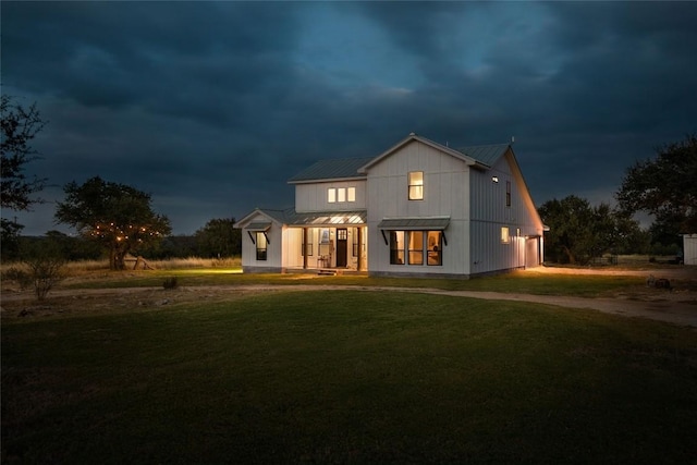 modern farmhouse style home featuring metal roof, dirt driveway, covered porch, a front yard, and a standing seam roof