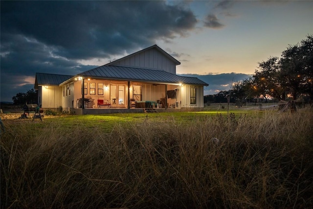 back of property featuring board and batten siding, a standing seam roof, metal roof, and covered porch