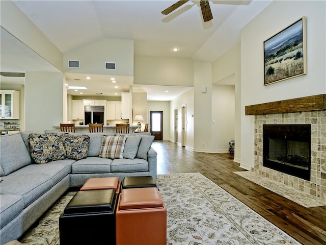 living area featuring a tiled fireplace, wood finished floors, visible vents, and baseboards