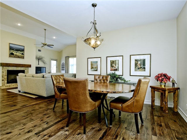 dining room with baseboards, dark wood-style flooring, vaulted ceiling, a fireplace, and recessed lighting