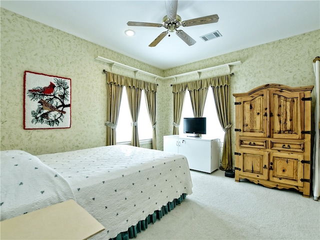 bedroom featuring a ceiling fan, light colored carpet, visible vents, and wallpapered walls