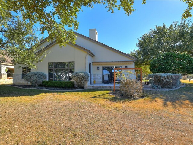 view of front of house with stone siding, a chimney, a front lawn, and stucco siding