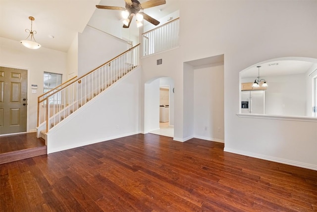 unfurnished living room with ceiling fan, a healthy amount of sunlight, a high ceiling, and hardwood / wood-style flooring