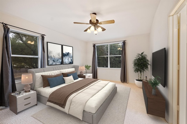 bedroom featuring light carpet, multiple windows, and ceiling fan