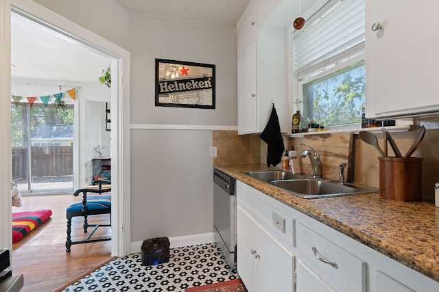 kitchen with sink, light hardwood / wood-style flooring, stainless steel dishwasher, decorative backsplash, and white cabinetry