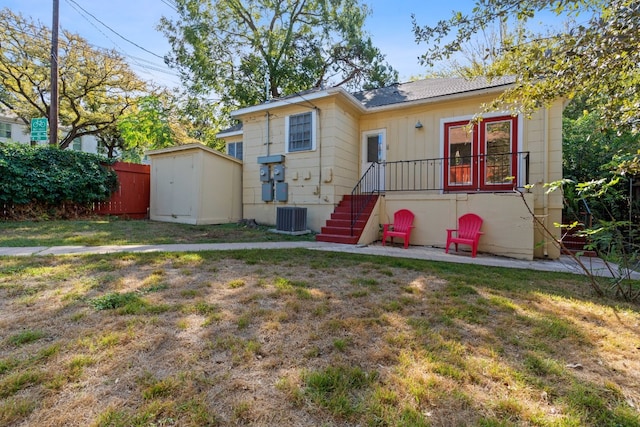 back of property with a yard, a shed, and cooling unit