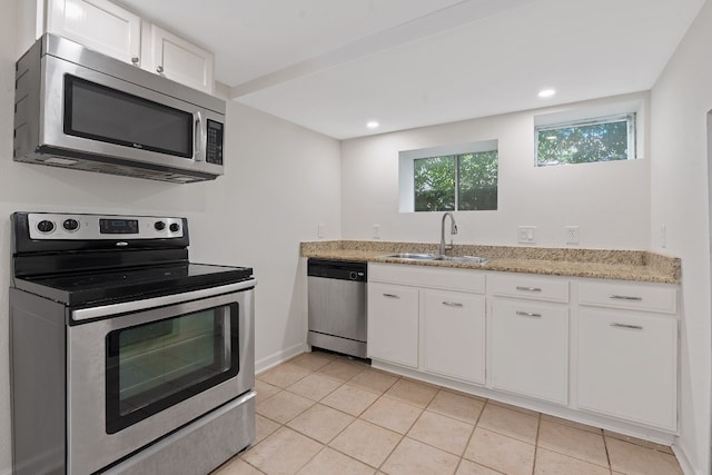 kitchen featuring white cabinets, appliances with stainless steel finishes, light tile patterned floors, and sink