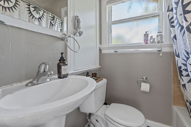 full bathroom with shower / bath combination with curtain, toilet, sink, and tile walls