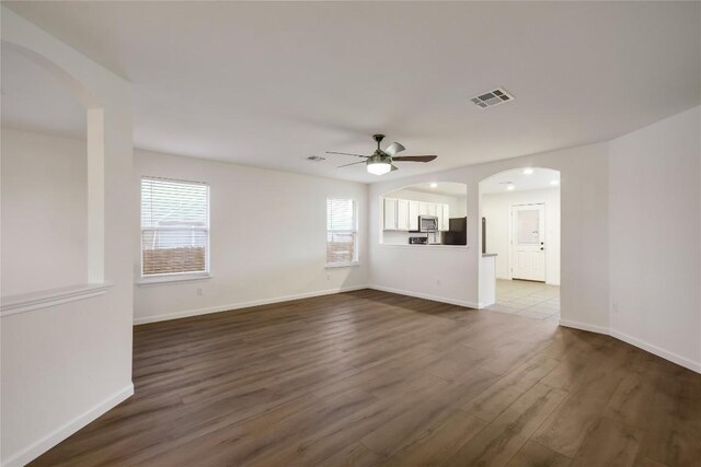 unfurnished living room with ceiling fan and dark wood-type flooring