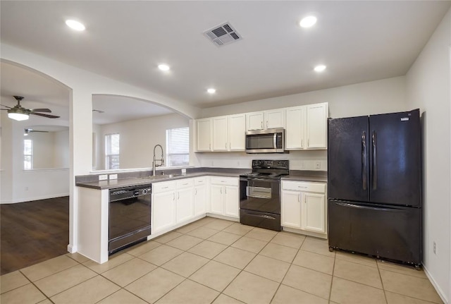 kitchen featuring visible vents, a ceiling fan, dark countertops, black appliances, and a sink