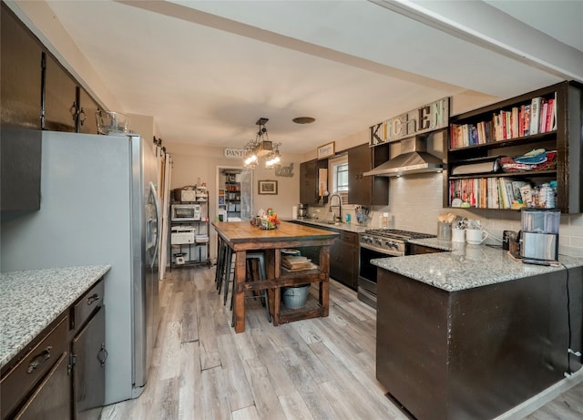 kitchen featuring tasteful backsplash, light hardwood / wood-style flooring, range hood, a notable chandelier, and appliances with stainless steel finishes