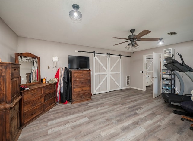 home office with light wood-type flooring, a barn door, and ceiling fan