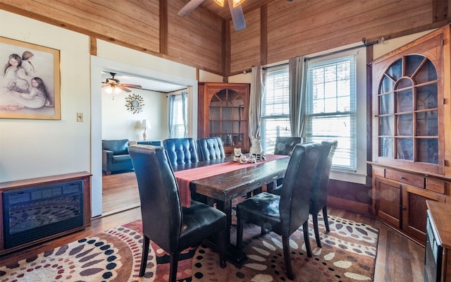 dining space with beam ceiling, hardwood / wood-style flooring, plenty of natural light, and wooden walls