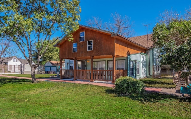 rear view of house featuring covered porch and a lawn