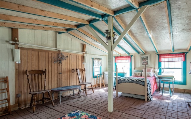 bedroom featuring wooden walls and lofted ceiling