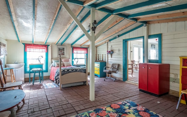 bedroom with vaulted ceiling and wooden walls