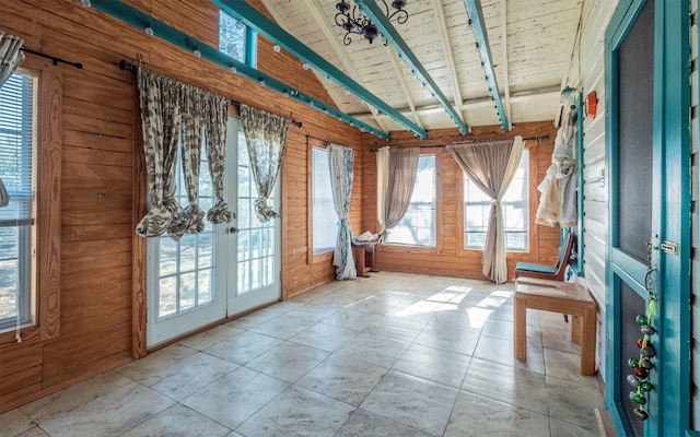 interior space with wood ceiling, wooden walls, french doors, and lofted ceiling with beams