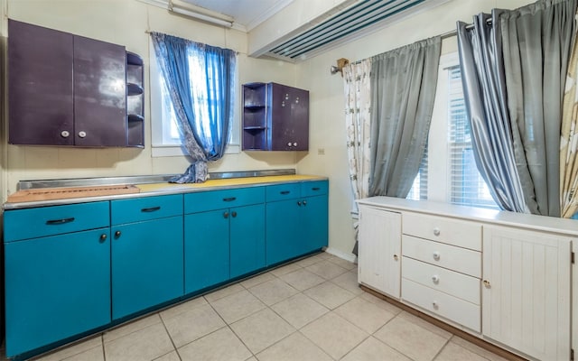 kitchen featuring blue cabinetry, plenty of natural light, light tile patterned floors, and ornamental molding