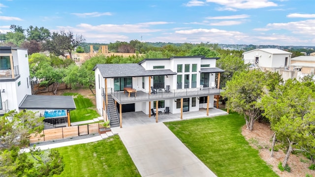 view of front facade featuring a balcony, a front lawn, and a patio area