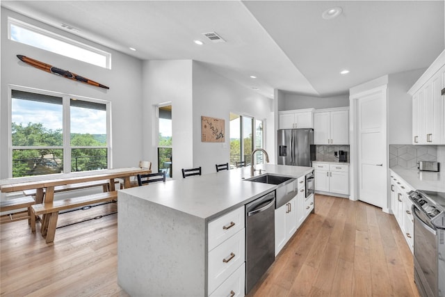 kitchen featuring white cabinets, a wealth of natural light, stainless steel appliances, and a kitchen island with sink