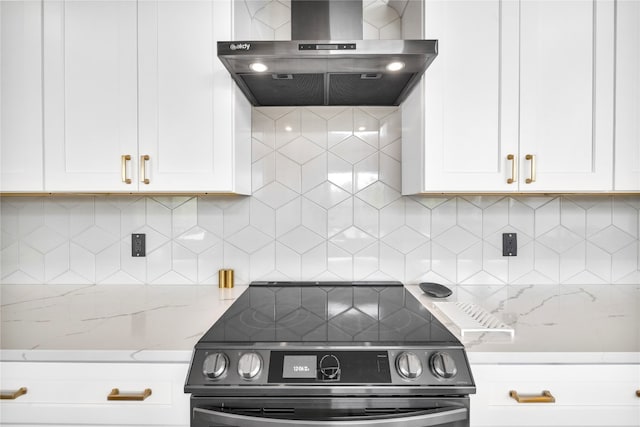 kitchen with black electric range, white cabinetry, wall chimney exhaust hood, and light stone counters