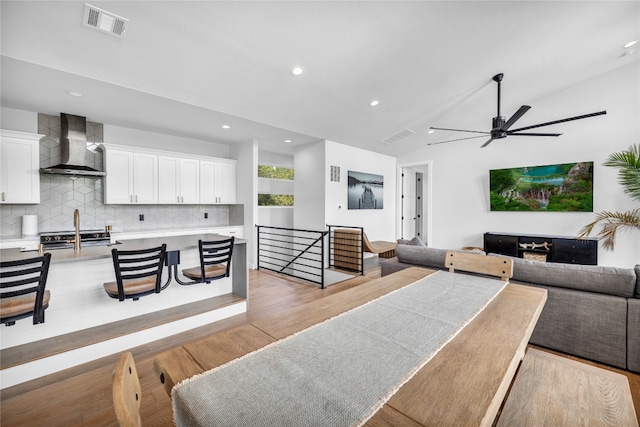 dining room with ceiling fan, light hardwood / wood-style flooring, and vaulted ceiling