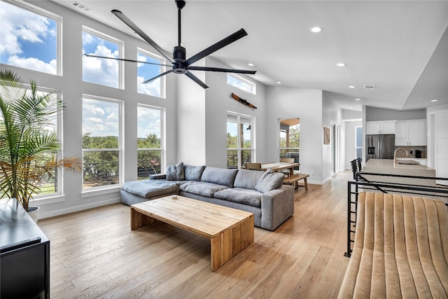 living room with a healthy amount of sunlight, light hardwood / wood-style floors, and high vaulted ceiling