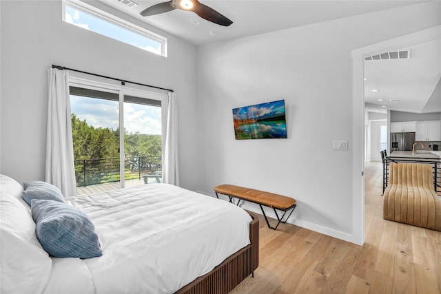 bedroom featuring multiple windows, stainless steel fridge, ceiling fan, and light hardwood / wood-style floors