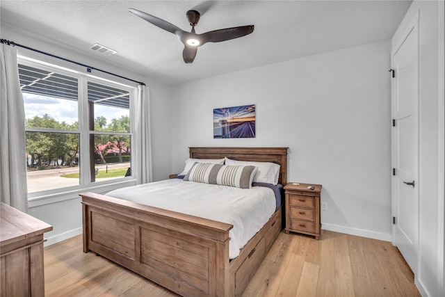 bedroom with ceiling fan, light hardwood / wood-style flooring, and a textured ceiling