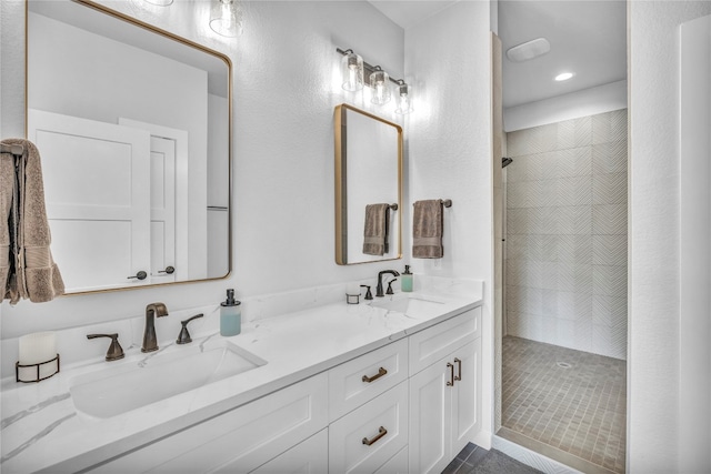 bathroom with tile patterned flooring, vanity, and a tile shower