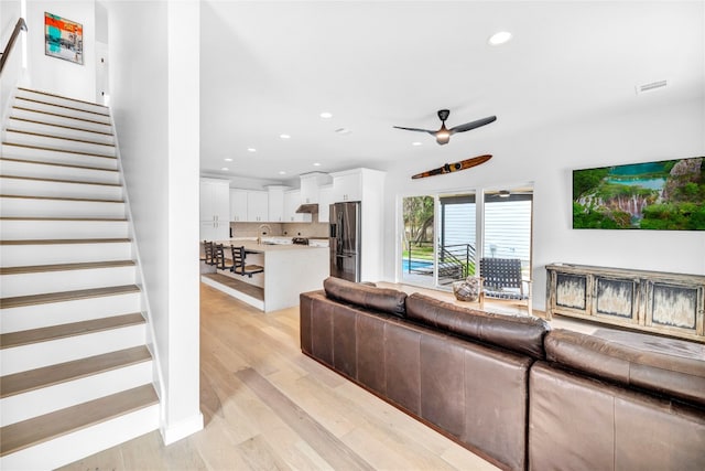 living room with ceiling fan, light wood-type flooring, and sink