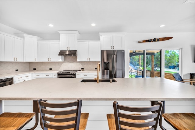 kitchen featuring a large island, sink, white cabinetry, stainless steel appliances, and a kitchen breakfast bar