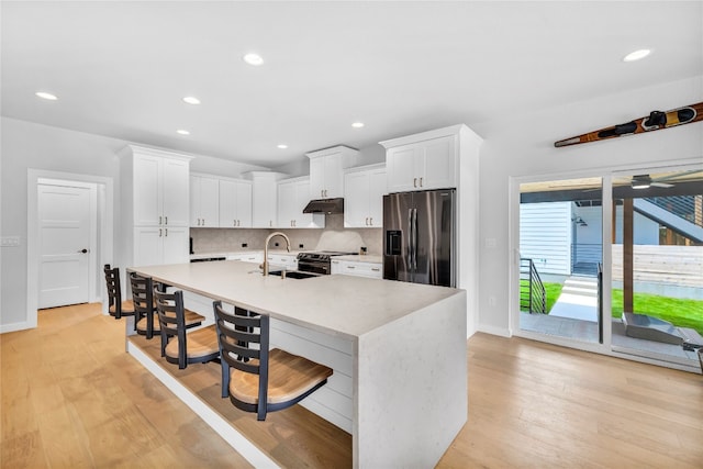 kitchen featuring white cabinetry, sink, stainless steel appliances, tasteful backsplash, and light wood-type flooring