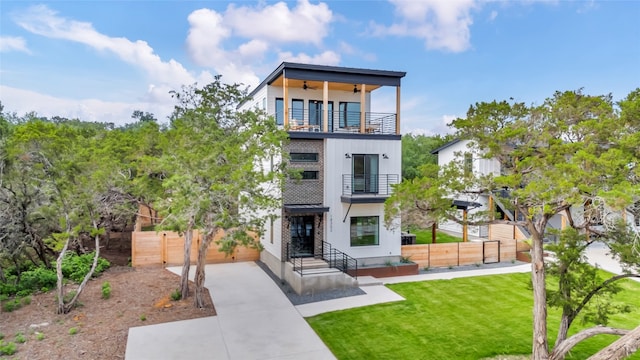 view of front of home with ceiling fan, a balcony, and a front yard