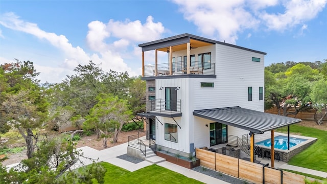 rear view of house with ceiling fan and a balcony