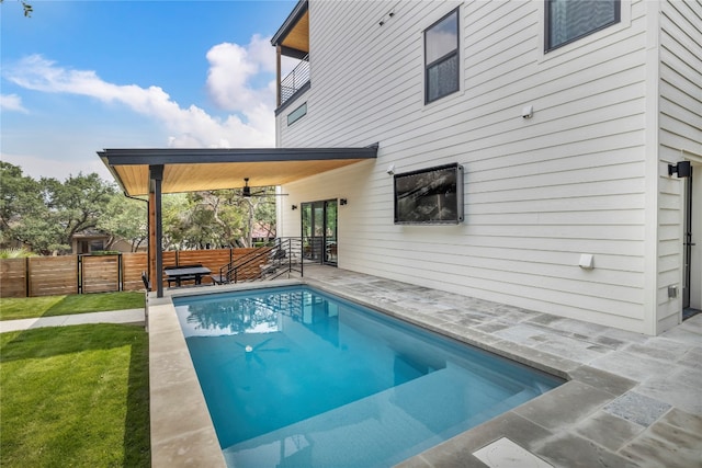 view of swimming pool featuring a lawn, ceiling fan, and a patio