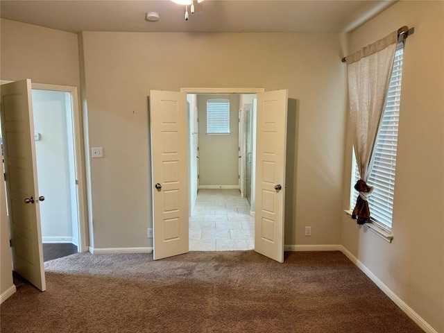unfurnished bedroom with carpet flooring, multiple windows, and baseboards
