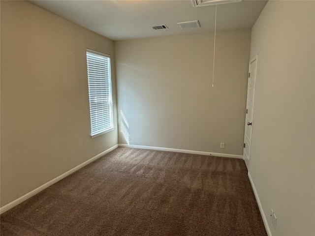carpeted empty room featuring attic access and baseboards