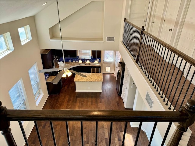 staircase with a high ceiling, wood finished floors, and a ceiling fan