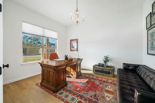 home office with light hardwood / wood-style floors and a notable chandelier