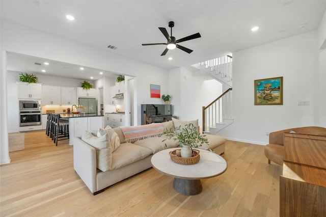 living room featuring ceiling fan, light hardwood / wood-style flooring, and sink